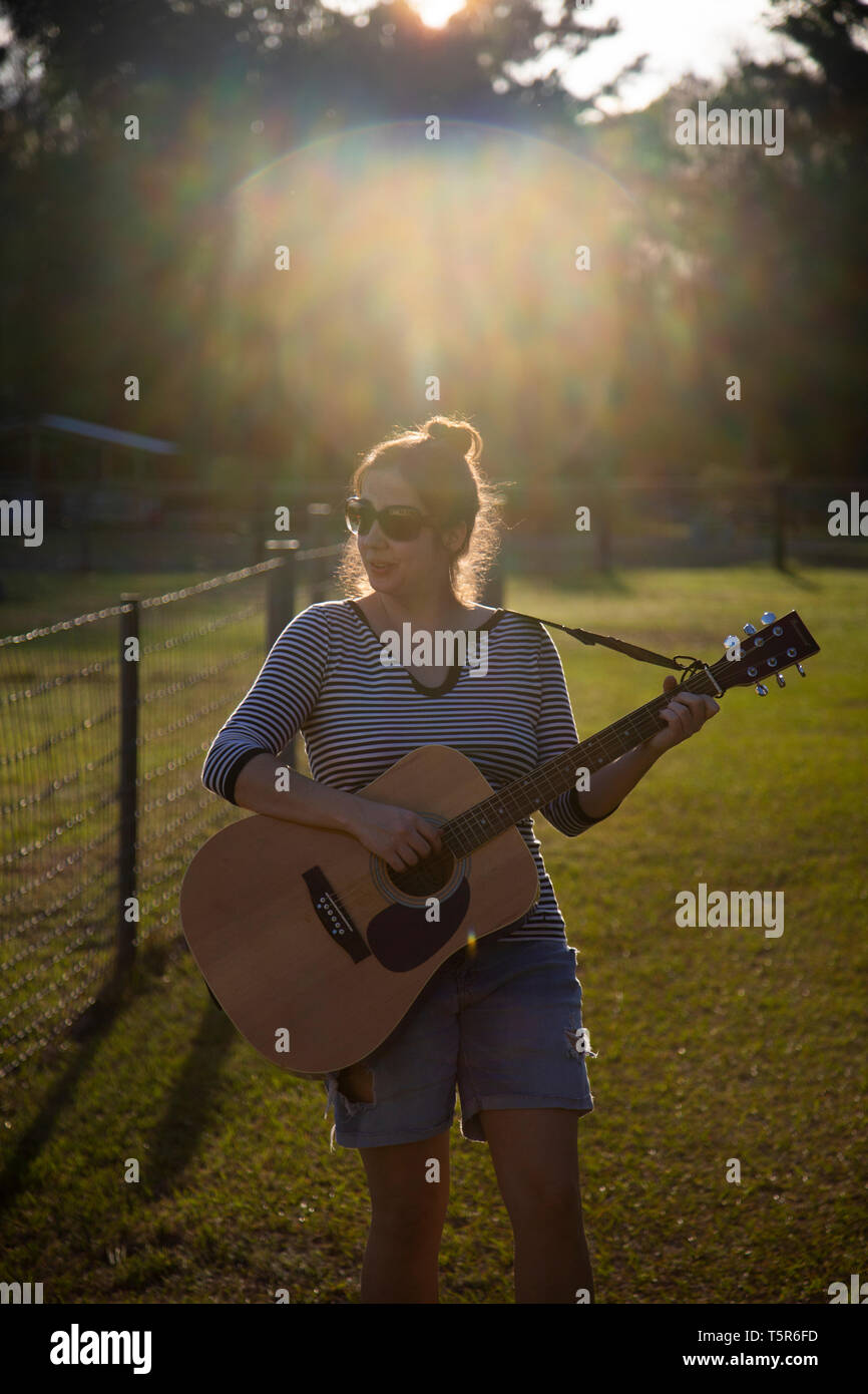 Junge Frau mit Gitarre in einem Feld Stockfoto