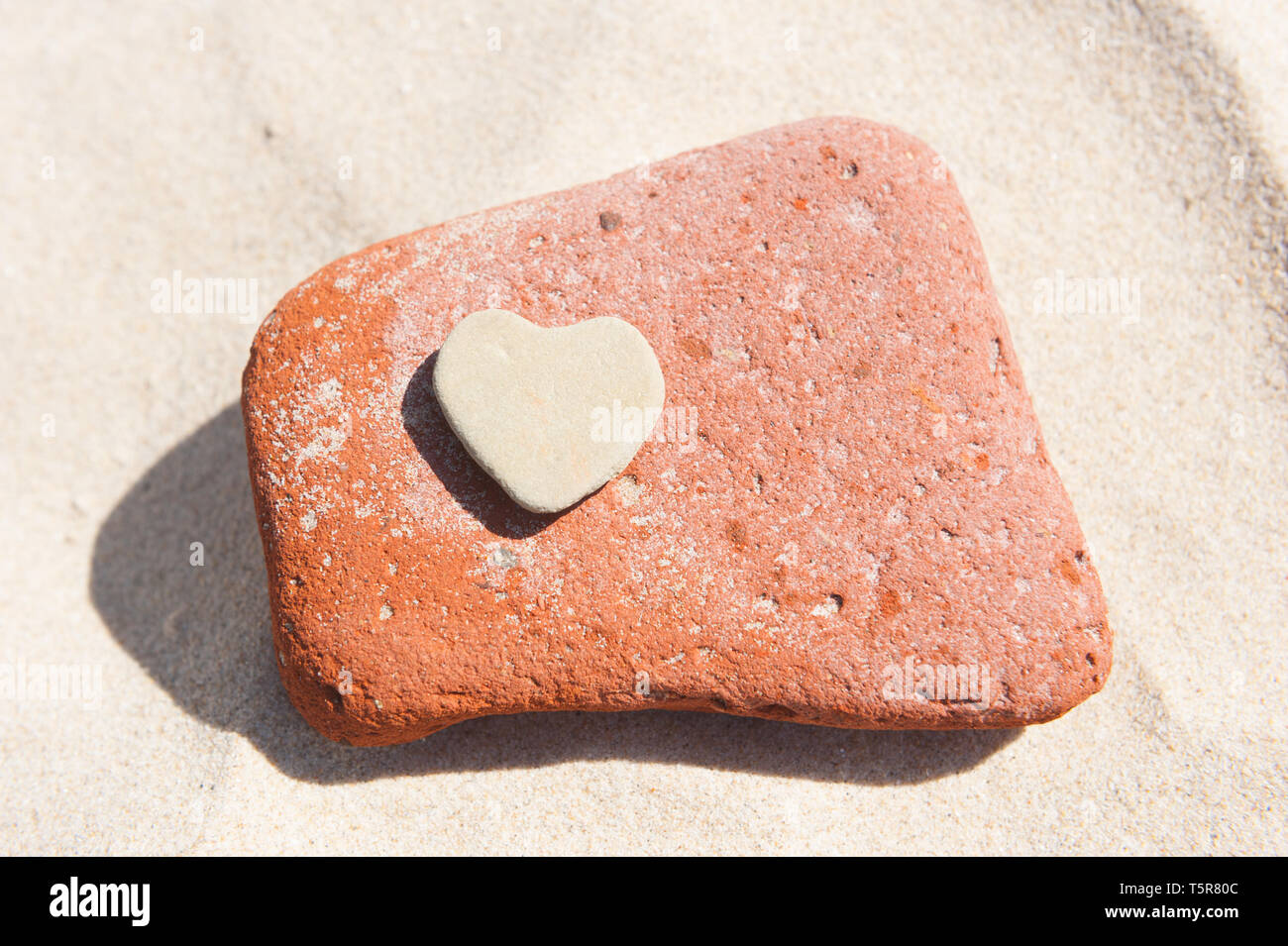 Herz aus Stein auf einem Sandstrand Stockfoto