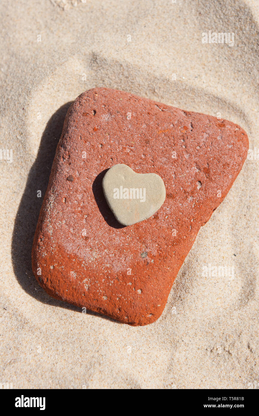 Herz aus Stein auf einem Sandstrand Stockfoto
