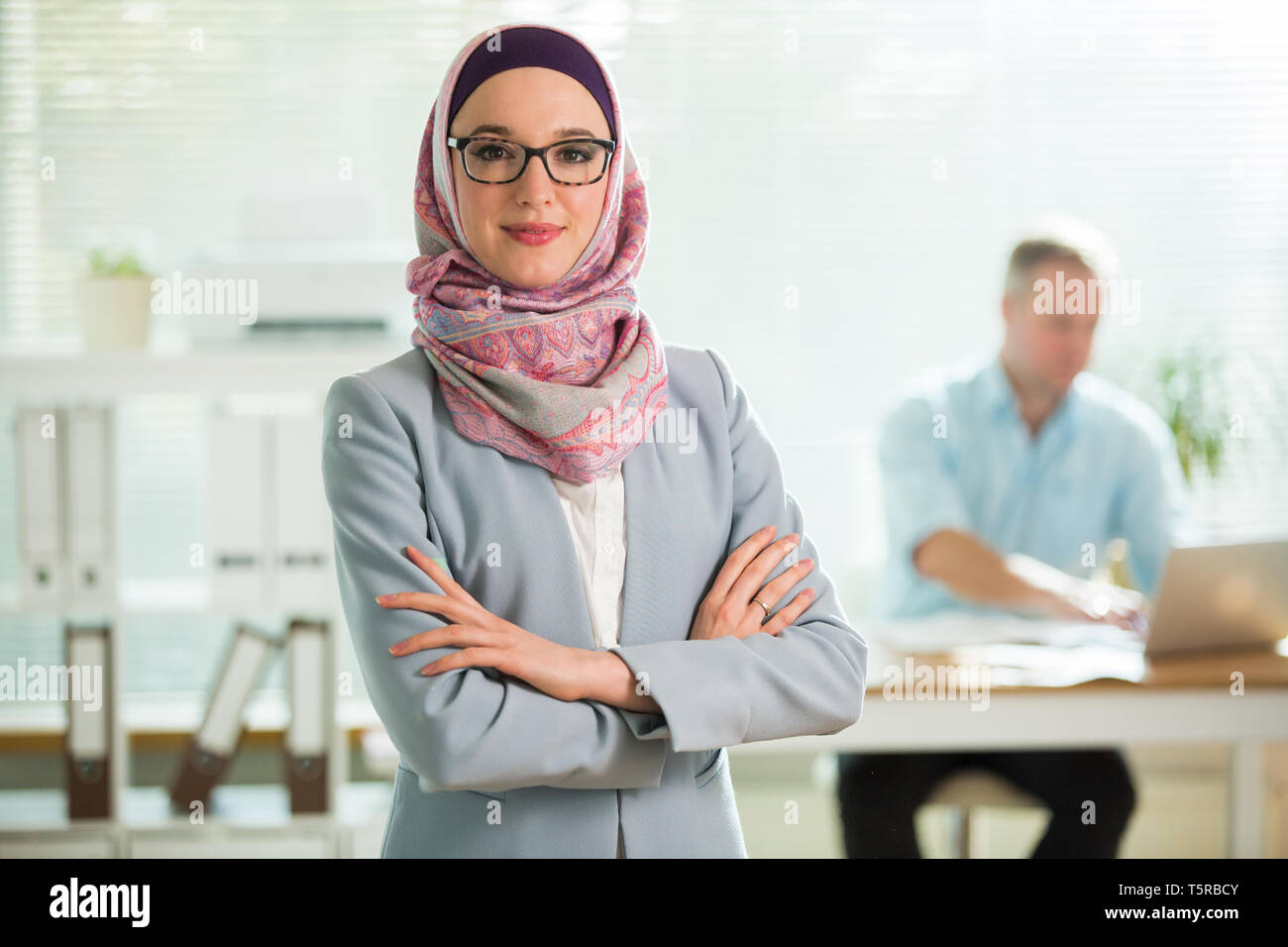Schöne junge berufstätige Frau im Hijab, Anzug und Brille in Büro,  lächelnd. Portrait von zuversichtlich muslimischen Geschäftsfrau. Moderne  Büro wit Stockfotografie - Alamy