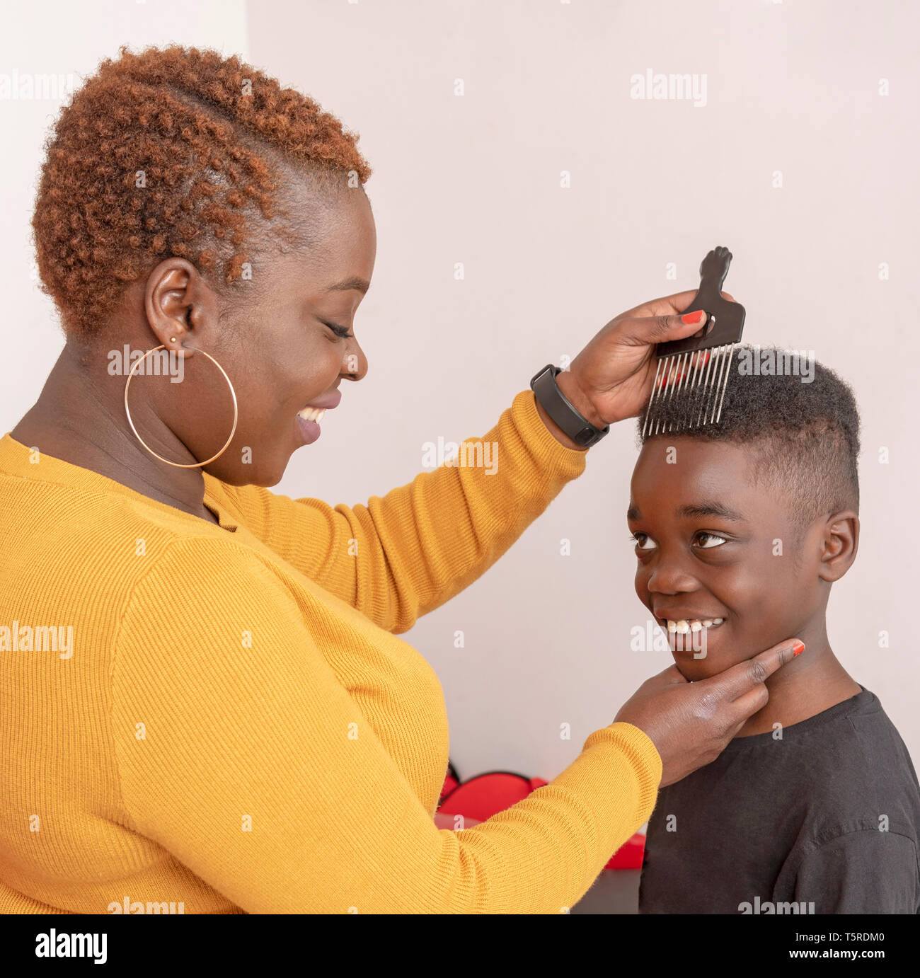 Andover, Hampshire, England, UK. April 2019. 9 Jahre alter Junge mit dem lockigen Haar mit seiner Mutter mit einem breiten Zahn afro Kamm für die Haare. Stockfoto