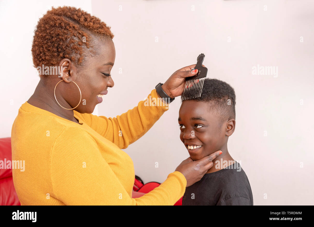 Andover, Hampshire, England, UK. April 2019. 9 Jahre alter Junge mit dem lockigen Haar mit seiner Mutter mit einem breiten Zahn afro Kamm für die Haare. Stockfoto