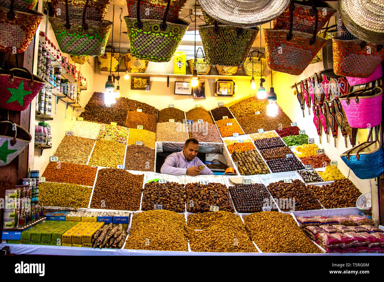 Die standbesitzer nimmt einen Bruch mit dem Verkauf von Kräutern und Gewürzen im Souk in Marrakesch sein Handy zu prüfen. Stockfoto