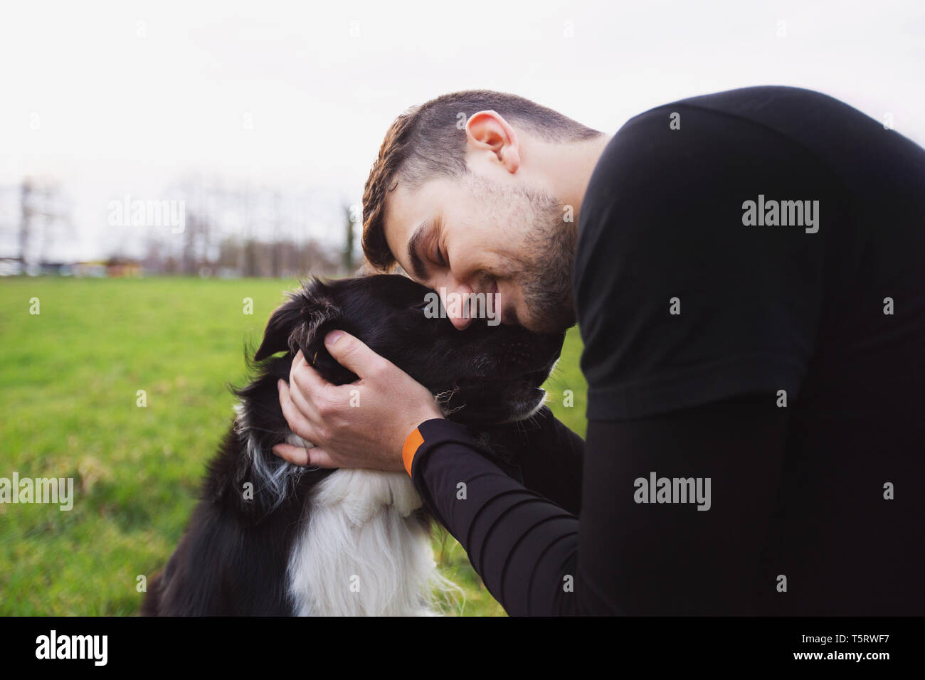 Der Mensch seine Border Collie Hund umarmt. Die jungen Besitzer Umarmungen seiner Haustiere. Freundschaft zwischen Besitzer und Hund. Tierische liebe Konzept. Stockfoto