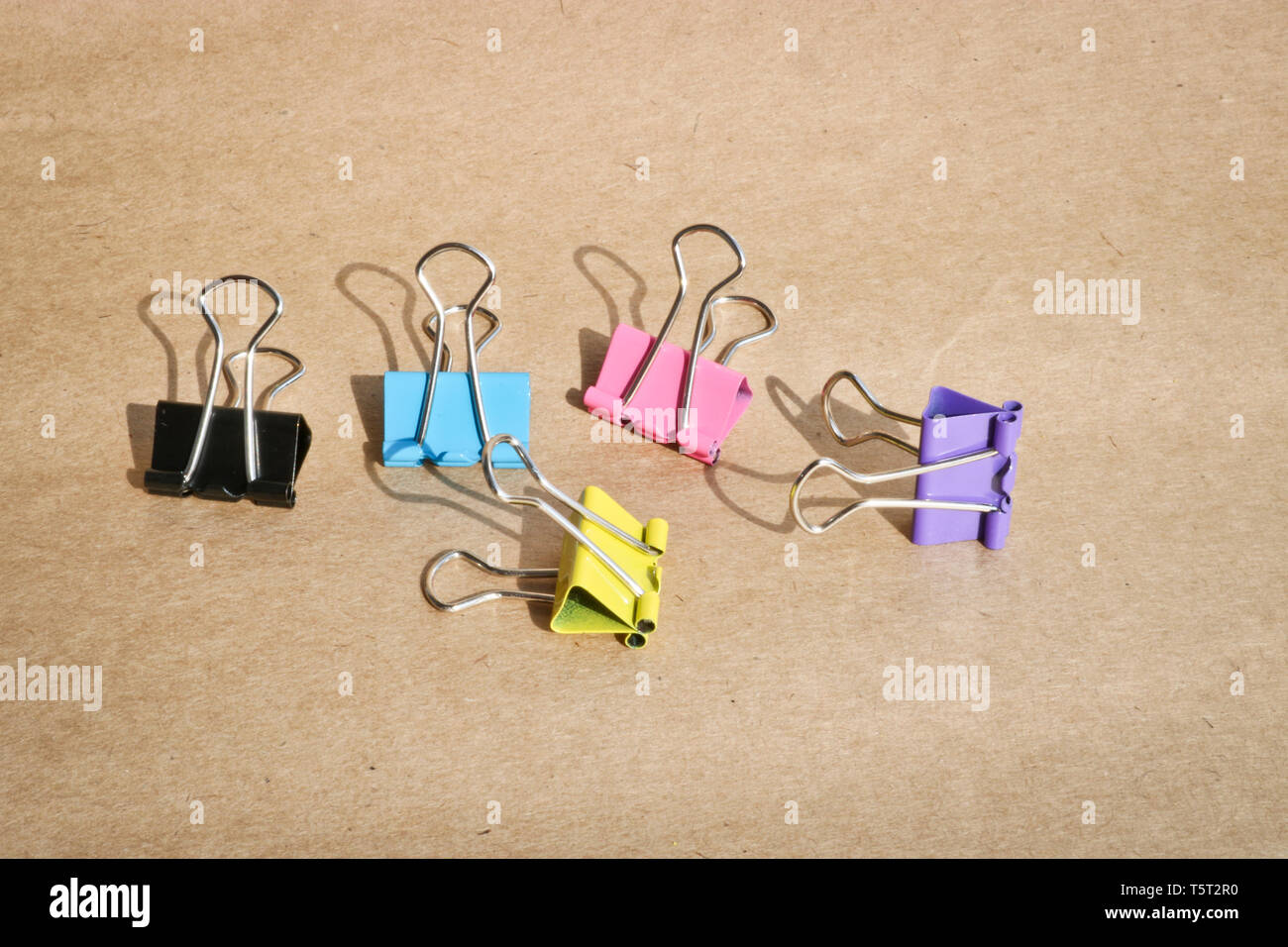 Clips für Papier in verschiedenen Farben auf dem Hintergrund des rauen braun Kraftpapier. Schreibwaren. Kopieren mit Platz für Text. Stockfoto