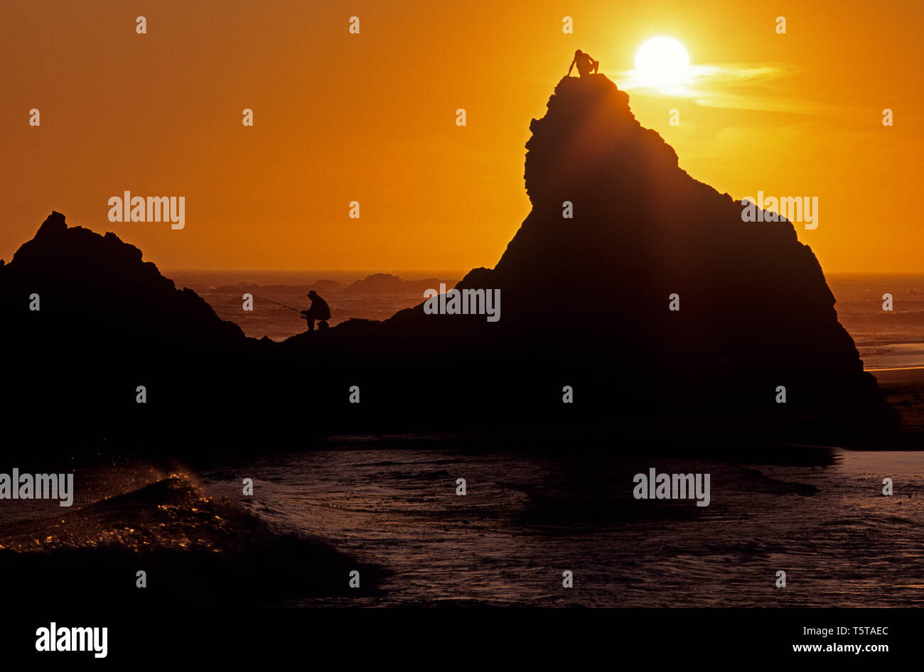 Southern Oregon Küste mit Silhouettiert Felsformationen und Fischer sitzen auf den Felsen dramatischer Sonnenuntergang Harris Beach State Park Oregon State USA Stockfoto