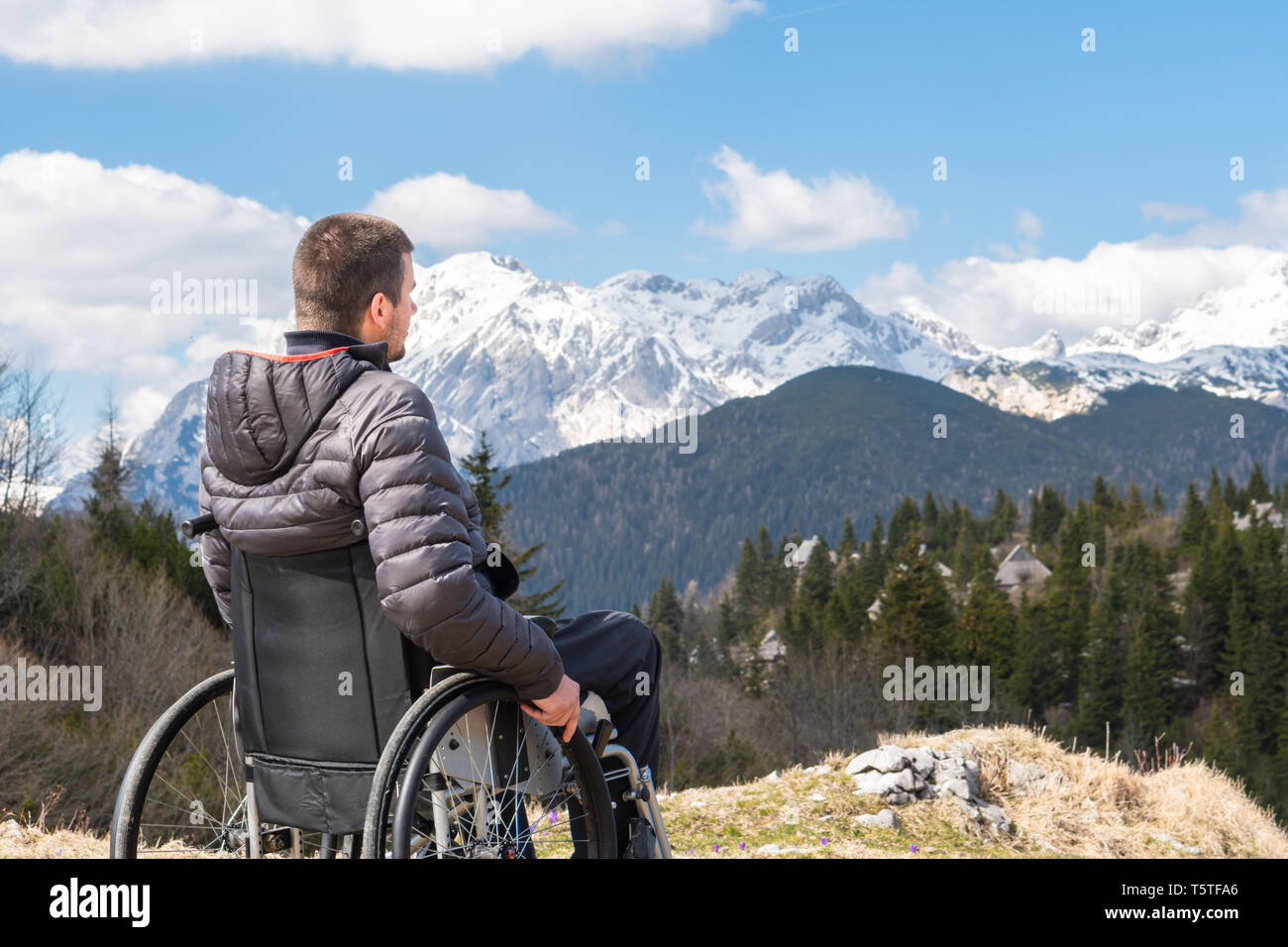 Foto von jungen behinderten Mann im Rollstuhl in der freien Natur beobachten, Berge und Natur Stockfoto