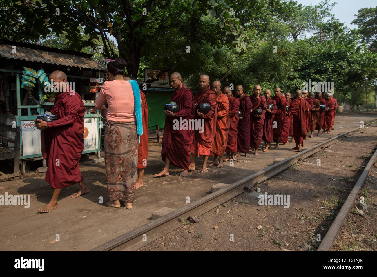 Buddhistische Mönche, die Almosen, die von einer Bahnstrecke in Thazi, Shan Staat, Myanmar. Stockfoto