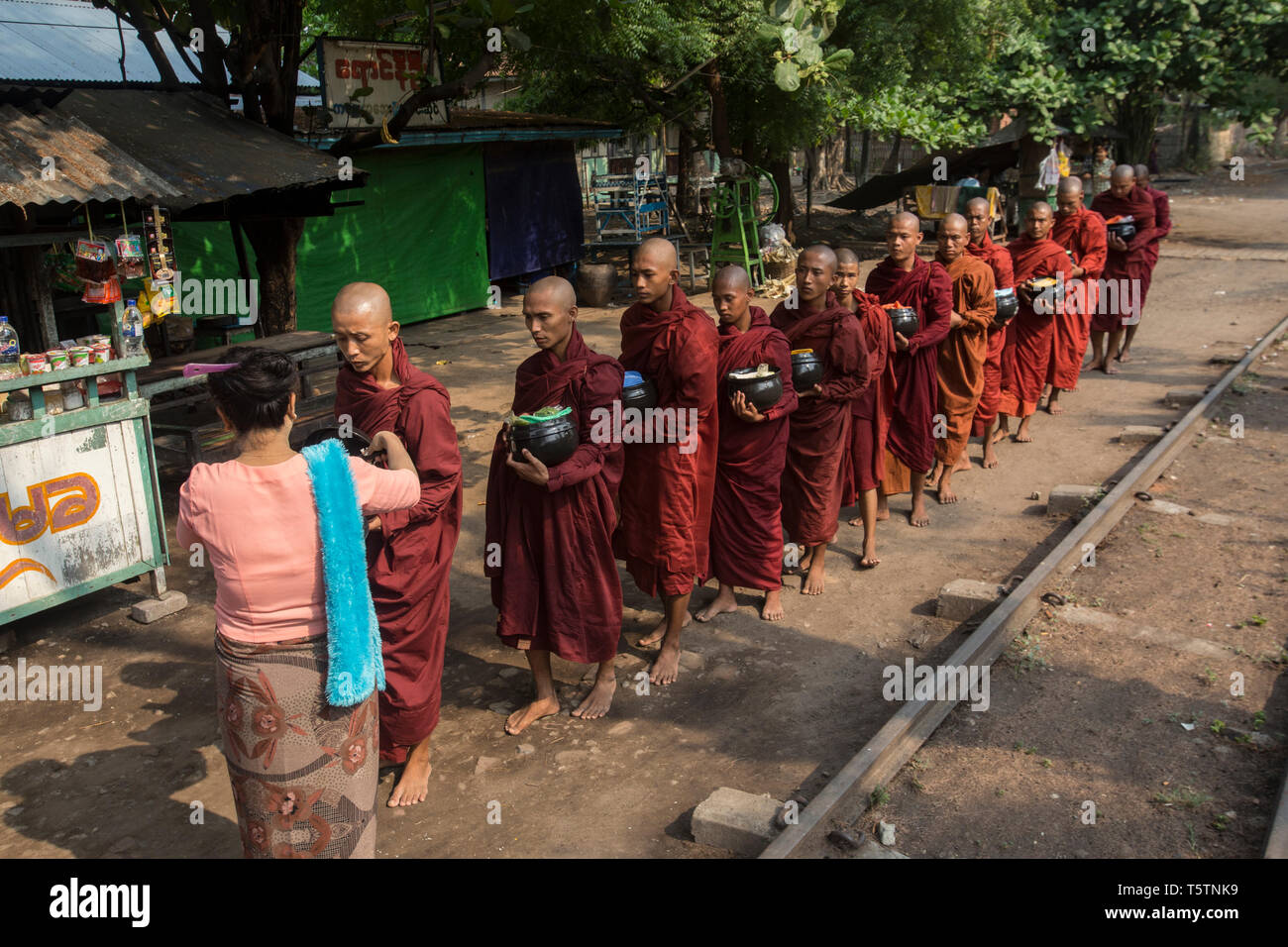 Buddhistische Mönche, die Almosen, die von einer Bahnstrecke in Thazi, Shan Staat, Myanmar. Stockfoto