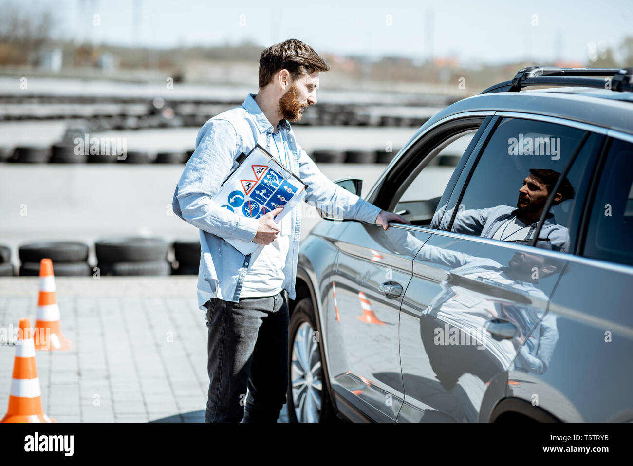 Kursleiter erläutert die Route Regelung der Ausbildung für einen Fahrer, der im Auto auf dem Trainingsplatz sitzt Stockfoto