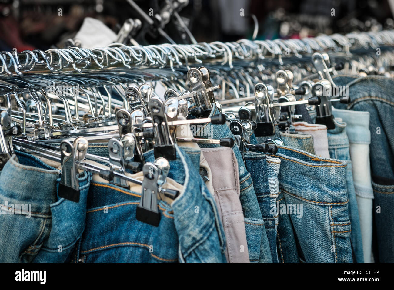 Jeans auf Kleiderbügeln, second hand Shop, Hosen closeup - Stockfoto