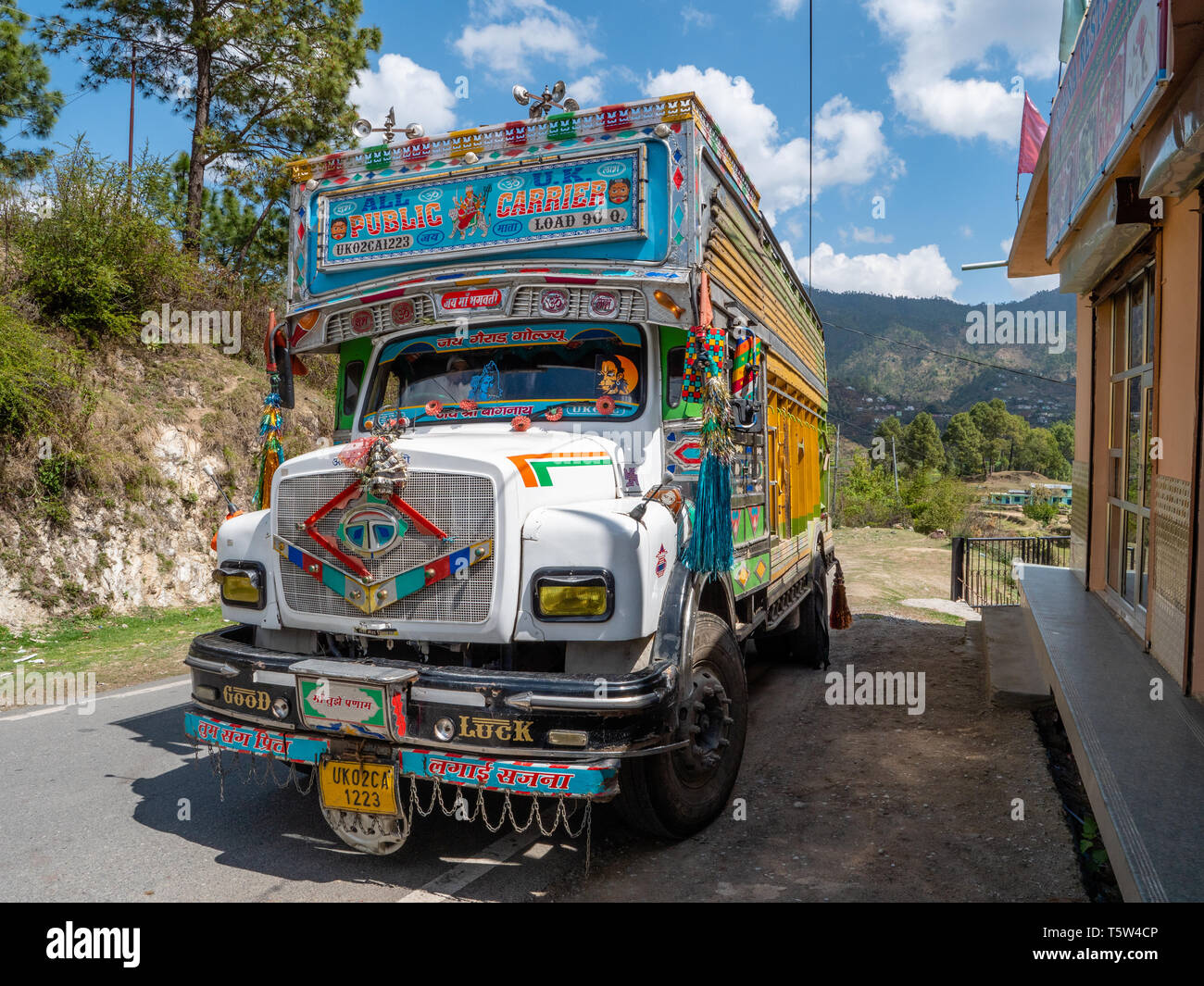 Bunt bemalte und aufwändig verzierte Güterverkehrs mit schweren Lastkraftwagen auf einer Straße durch die binsar Region Uttarakhand im Norden Indiens Stockfoto