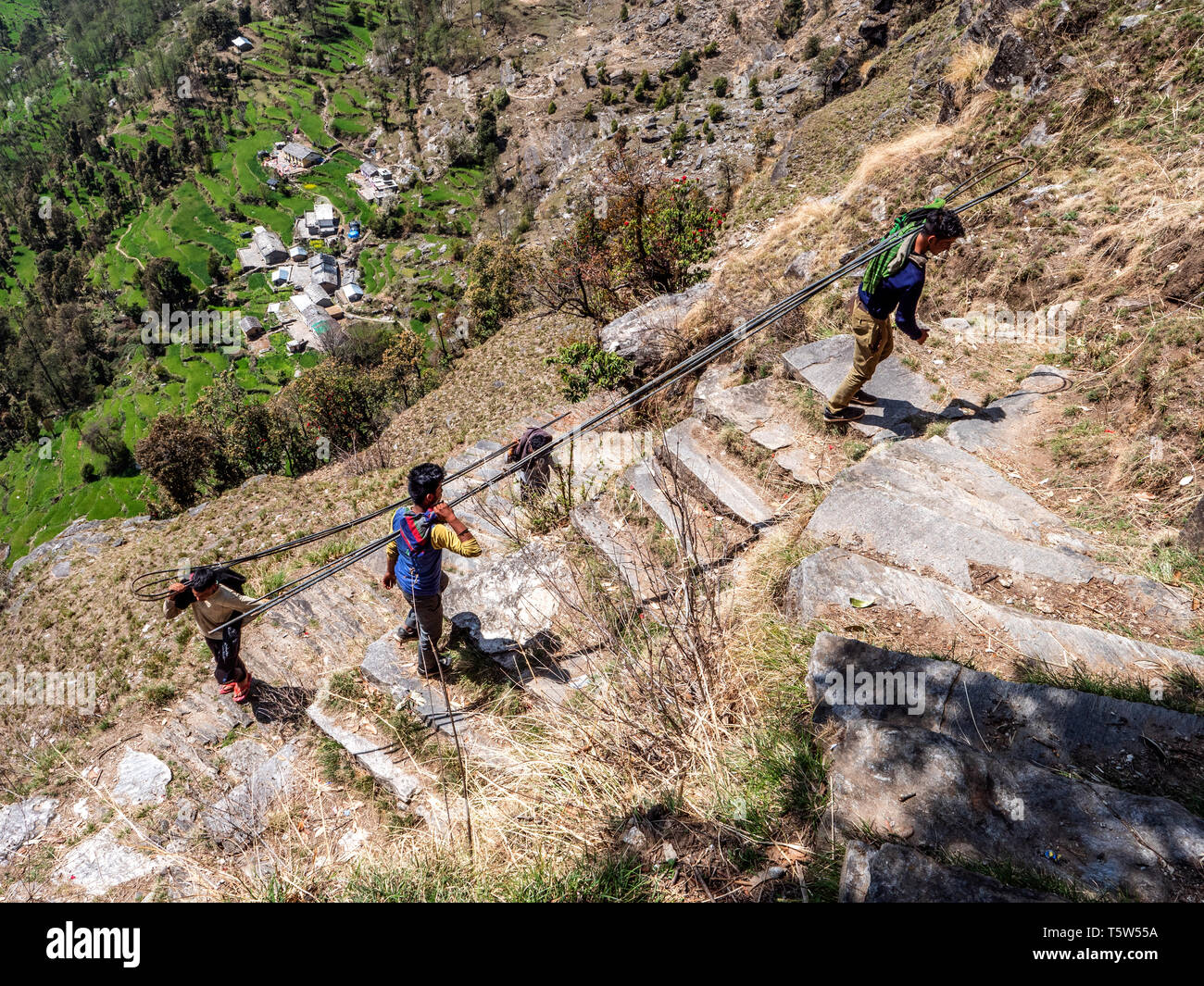 Junge Männer tragen vier Meter langen Stahl verstärken Stangen die Punishingly steilen "tausend Schritte weg von Supi zu Khaljuni Uttarakhand Hilamlayas Stockfoto