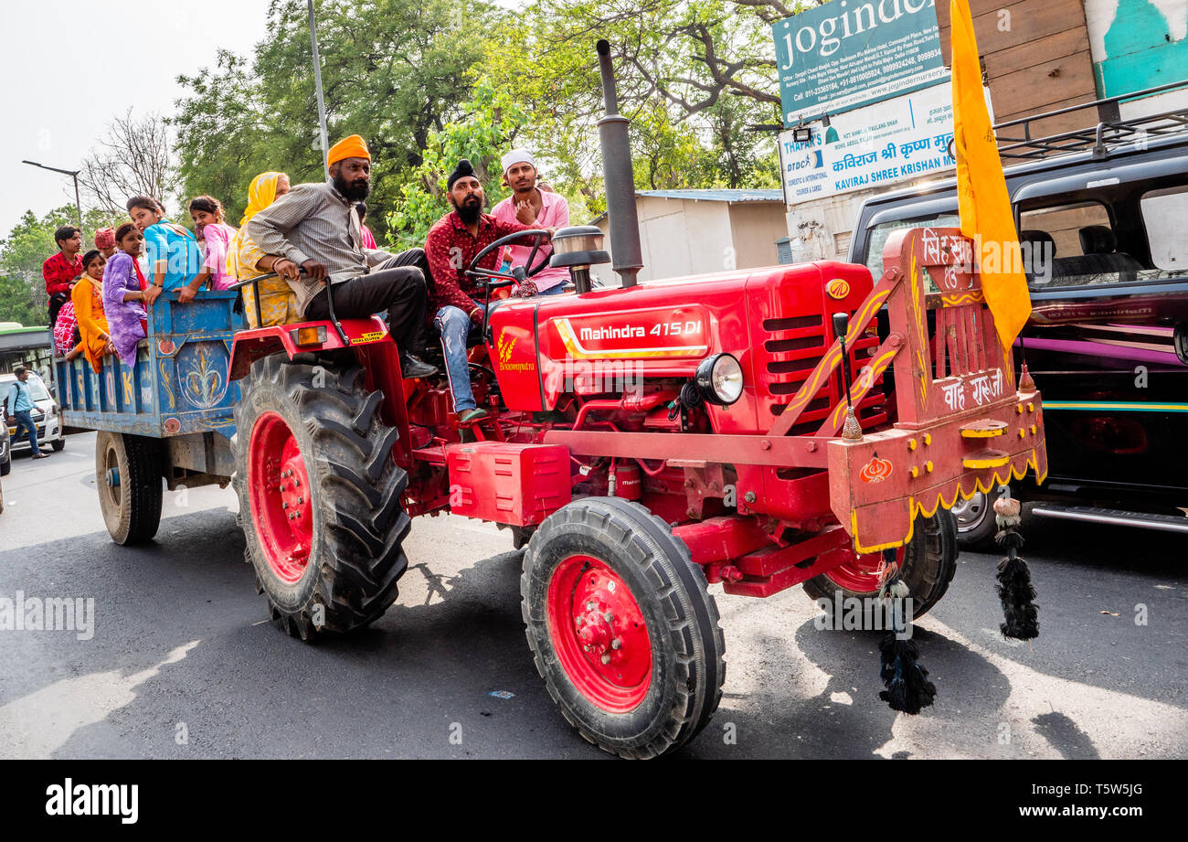 Hochzeitsfeier wird durch die belebten Straßen von Delhi im nördlichen Indien auf einem Traktor und Anhänger transportiert Stockfoto
