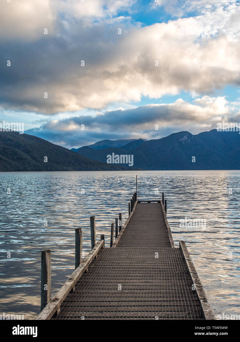 Wharf und Wellen des blauen Abendlicht auf ruhigem Wasser, wilde Berglandschaft, Lake Hauroko, Fiordland National Park, Southland, Neuseeland Stockfoto