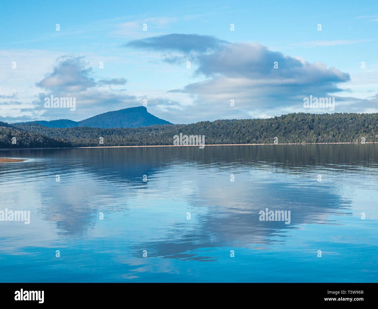 Wolken und blauer Himmel in ruhigem Wasser reflektiert, die fernen Hügel, ein herbsttag am Lake Hauroko, Fiordland National Park, Southland, Neuseeland Stockfoto