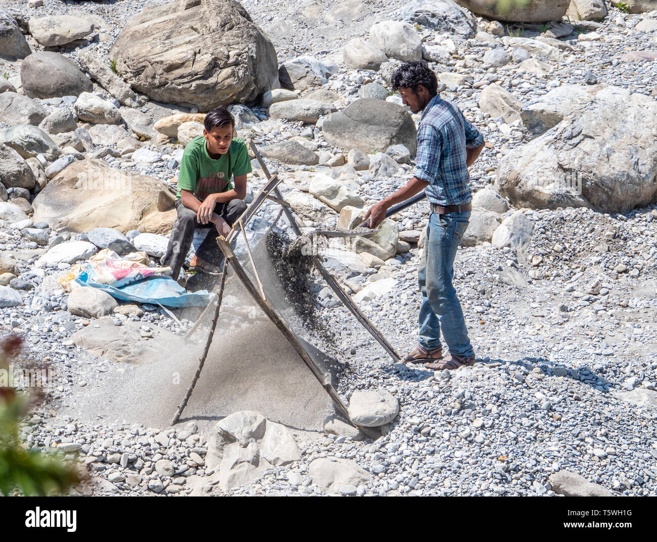 Junge Männer sieben Sand für den Bau von River Kies auf dem Fluss in der Nähe von Bageshwar Saryu in Uttarakhand im Norden Indiens Stockfoto