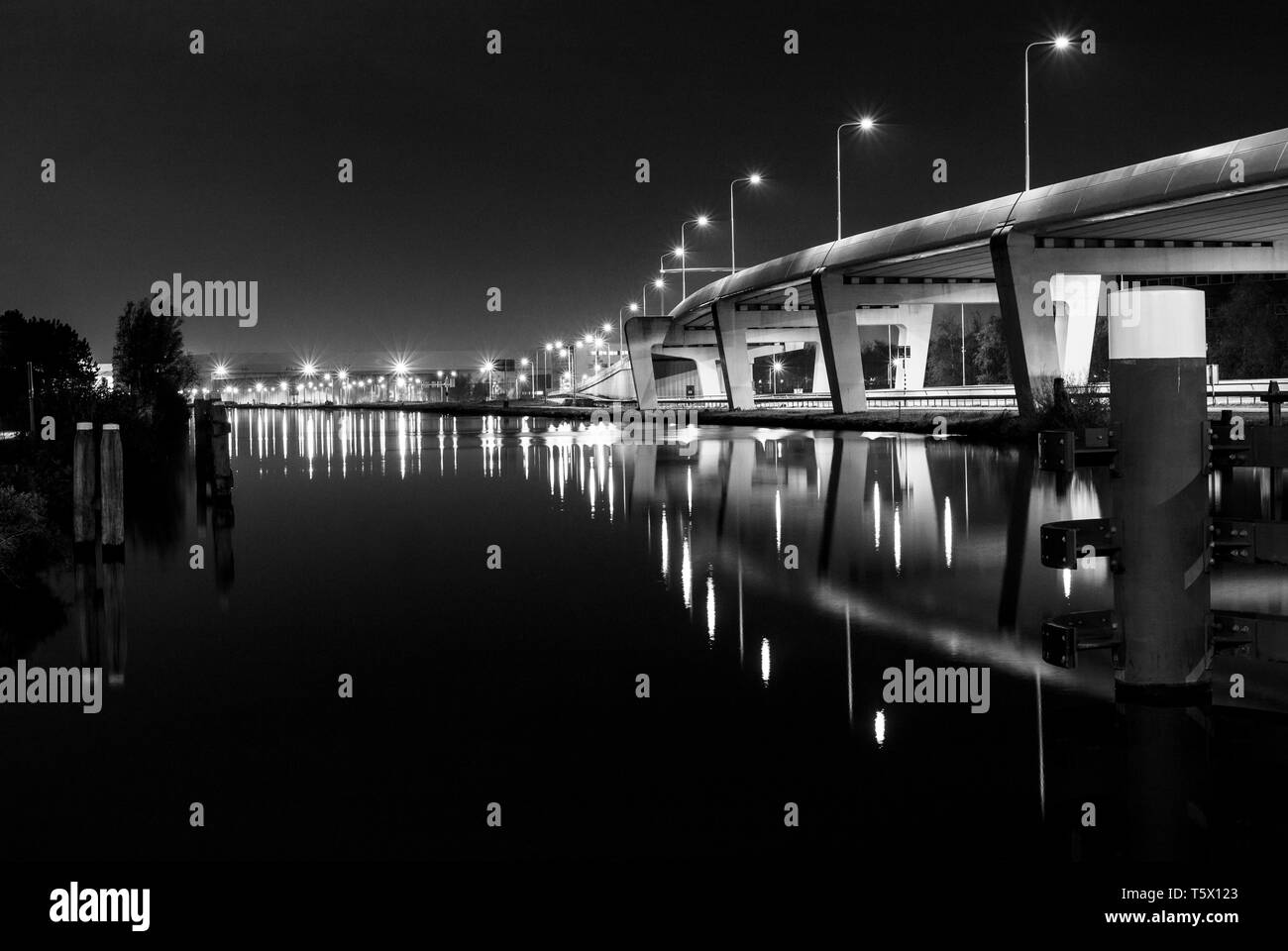 Brücke in Amsterdam bei Nacht in Schwarz und Weiß mit Reflexion der Straßenbeleuchtung Stockfoto