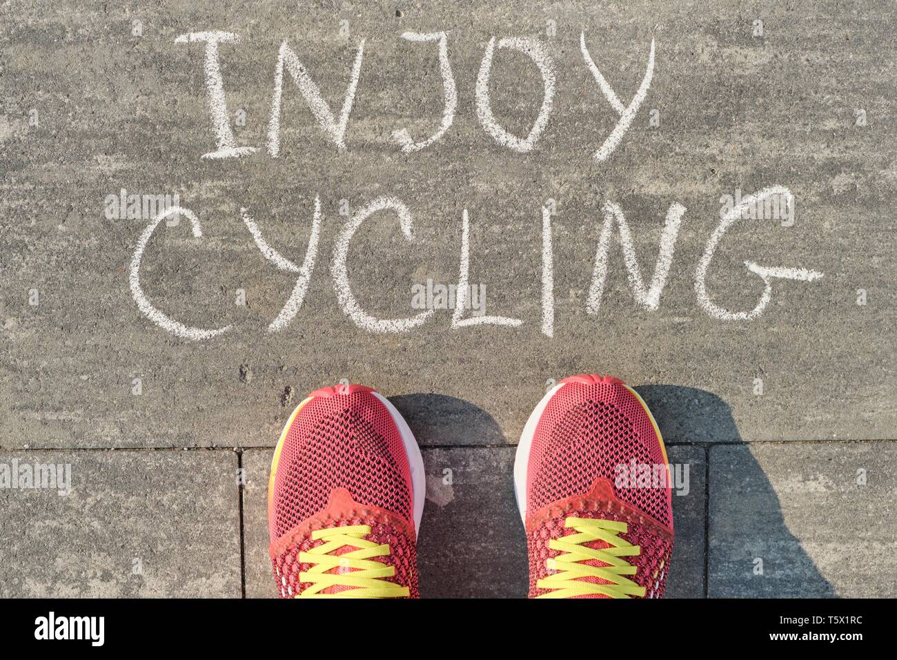 Radfahren, Text auf grau Bürgersteig mit Frau Beine in Sneakers, Ansicht von oben. Stockfoto