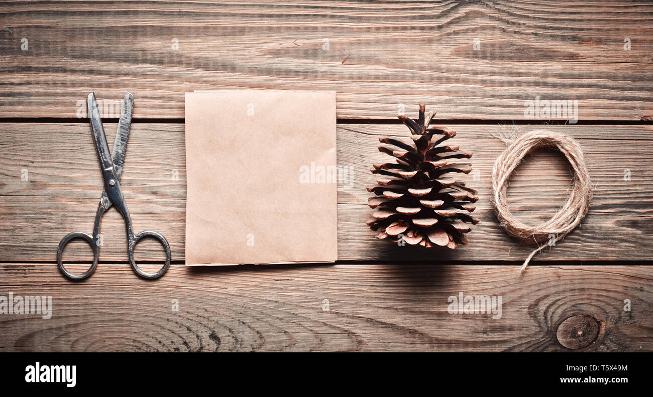 Werkzeuge für Heimwerker auf einen hölzernen Tisch: Papier, Schere, Gewinde, Kegel. Self-made Umschlag für Briefe. Ansicht von oben. Flach. Stockfoto