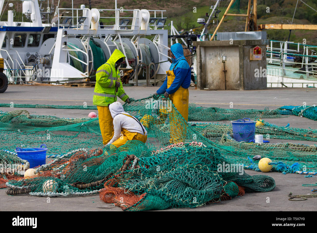 Fischer Ausbesserung oder Instandsetzung Fischernetze auf dem Steg am Kai Stockfoto