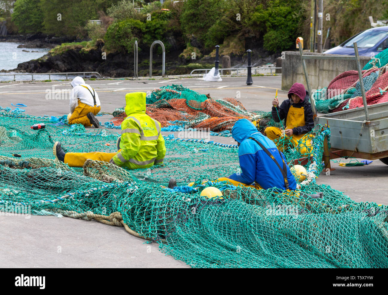 Fischer Ausbesserung oder Instandsetzung Fischernetze auf dem Steg am Kai Stockfoto