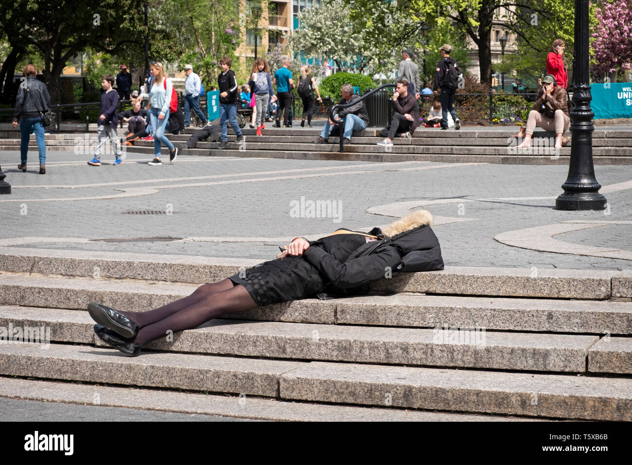 Ein anonymer gut gekleidete Frau in einen Mantel schlafen auf die Schritte am Union Square Park in Lower Manhattan, New York City. Stockfoto