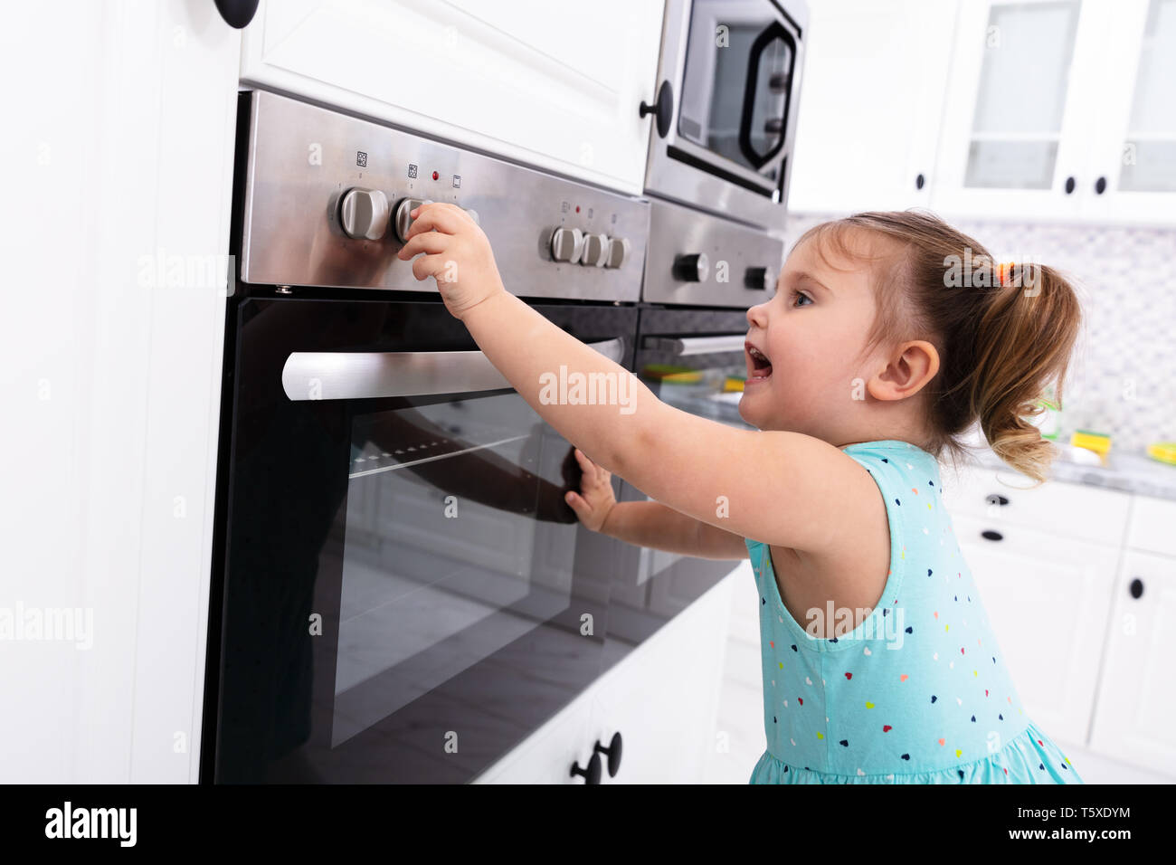 Kleine Mädchen spielen mit elektrischen Mikrowelle in der Küche Stockfoto