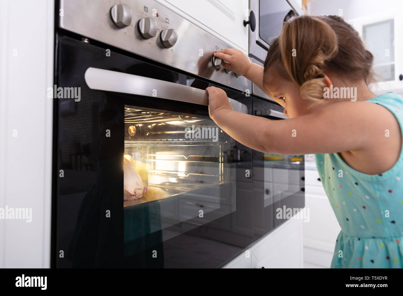 Kleine Mädchen spielen mit elektrischen Mikrowelle in der Küche Stockfoto