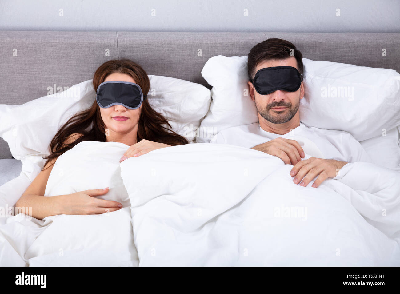 Junges Paar schlafend auf dem Bett mit Augenmaske im Schlafzimmer Stockfoto