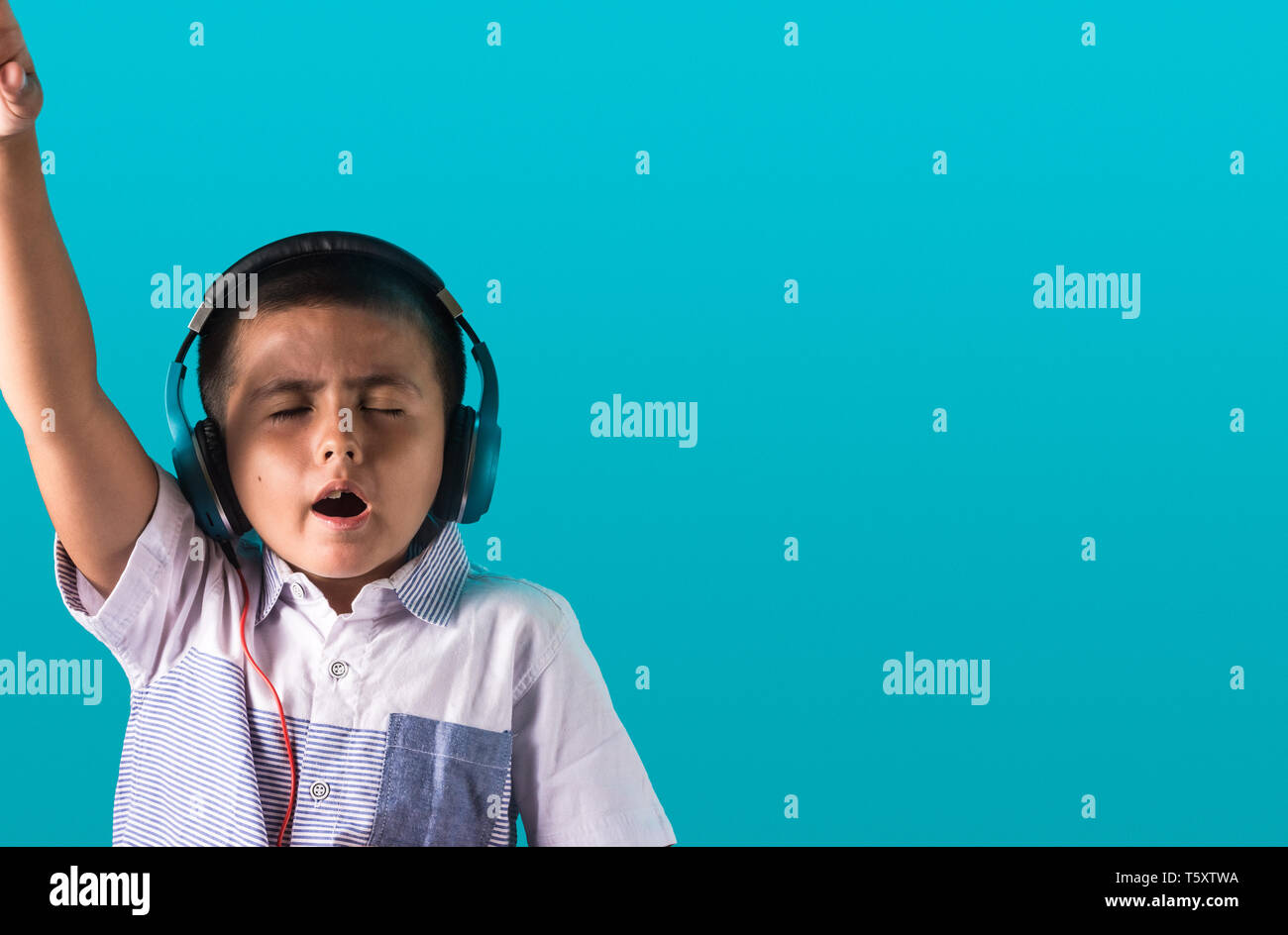 Kleine Jungen mit ausdrucksstarken Gesichts Hören von Musik über Kopfhörer Tanzen und Singen authentischen unposed Bild mit Kopie Platz für Text. Stockfoto