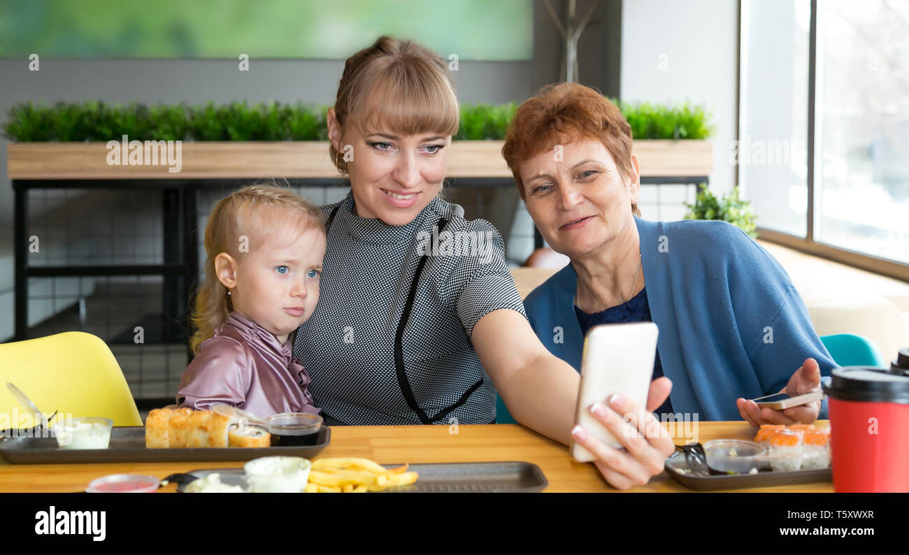 Eine junge Frau nimmt Bild von sich selbst auf einem Smartphone mit einem älteren Mutter und Tochter. Stockfoto