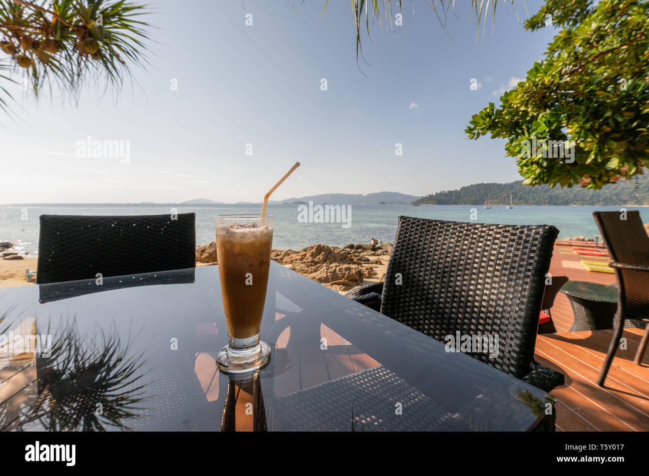 Eiskaffee auf Glas Tisch mit Meerblick und der Strand am Morgen Stockfoto