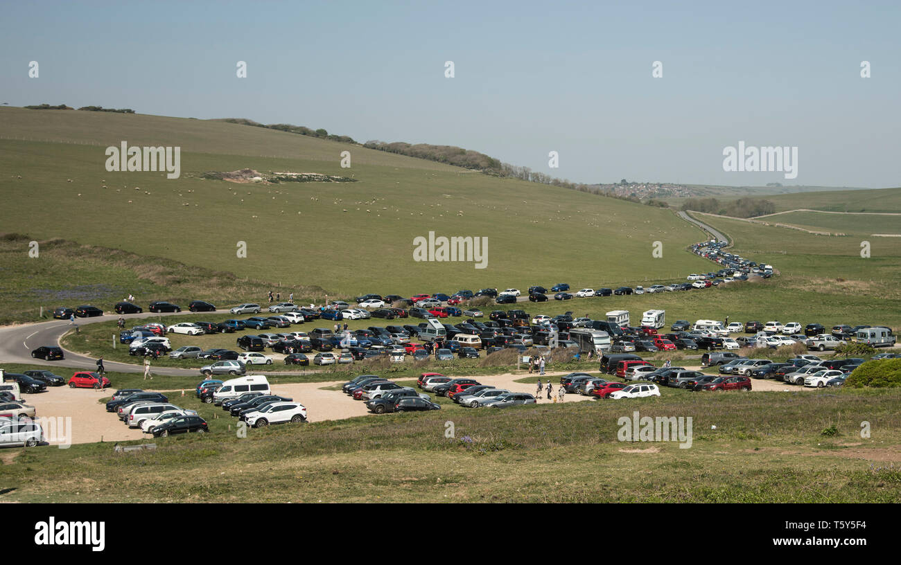 Fahrzeuge auf einem überfüllten Parkplatz und entlang der Straße, die zu einem beliebten Reiseziel an der South Downs Way East Sussex in der Nähe von Beachy Head geparkt Stockfoto