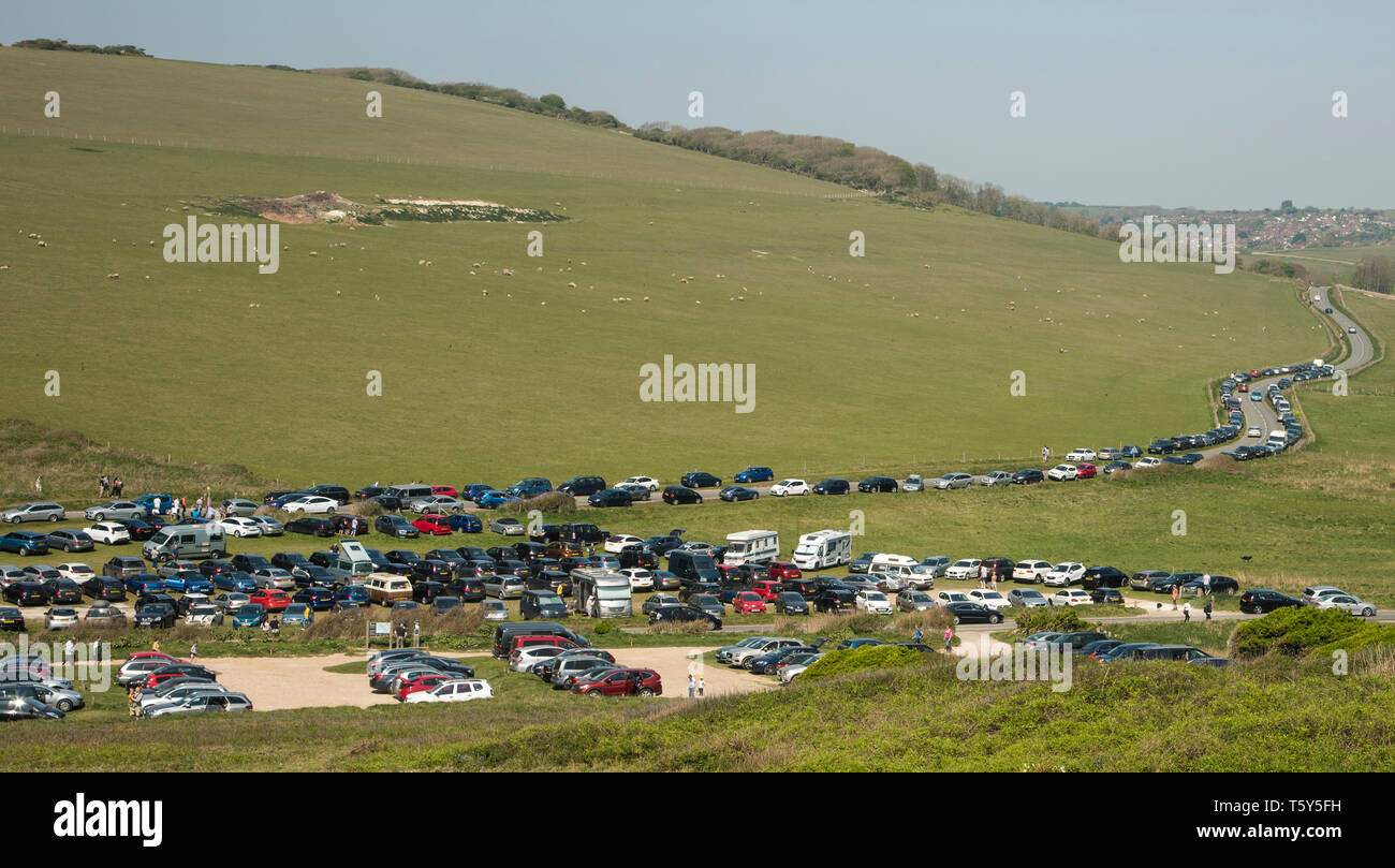 Fahrzeuge auf einem überfüllten Parkplatz und entlang der Straße, die zu einem beliebten Reiseziel an der South Downs Way East Sussex in der Nähe von Beachy Head geparkt Stockfoto