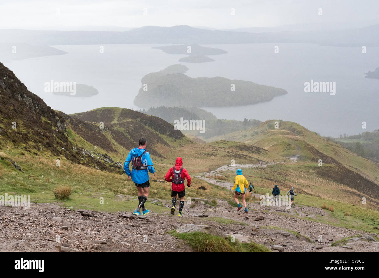 Conic Hill, Loch Lomond, Schottland, Großbritannien - 27 April 2019: Großbritannien Wetter - sehr schwere Duschen teilweise verdecken den Blick über Loch Lomond für Ultra Marathon Läufer absteigend Conic Hill in den frühen Phasen der 53 mile Highland Fling Rennen. Die beschwerliche Ultra Marathon Trail Rennen folgt dem Pfad der West Highland Way durch Loch Lomond und der Trossachs National Park zwischen Milngavie und Tyndrum. Credit: Kay Roxby/Alamy leben Nachrichten Stockfoto