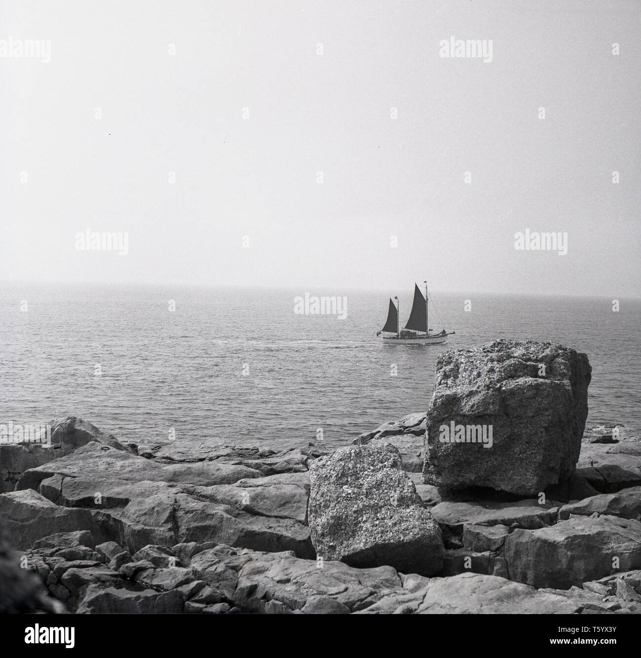 1940 s, historischen, ein Blick von den Felsen am TillyWhim Höhlen in der Nähe von Swanage über dem Meer mit einem Segel boot Pass, Dorset, England. Stockfoto