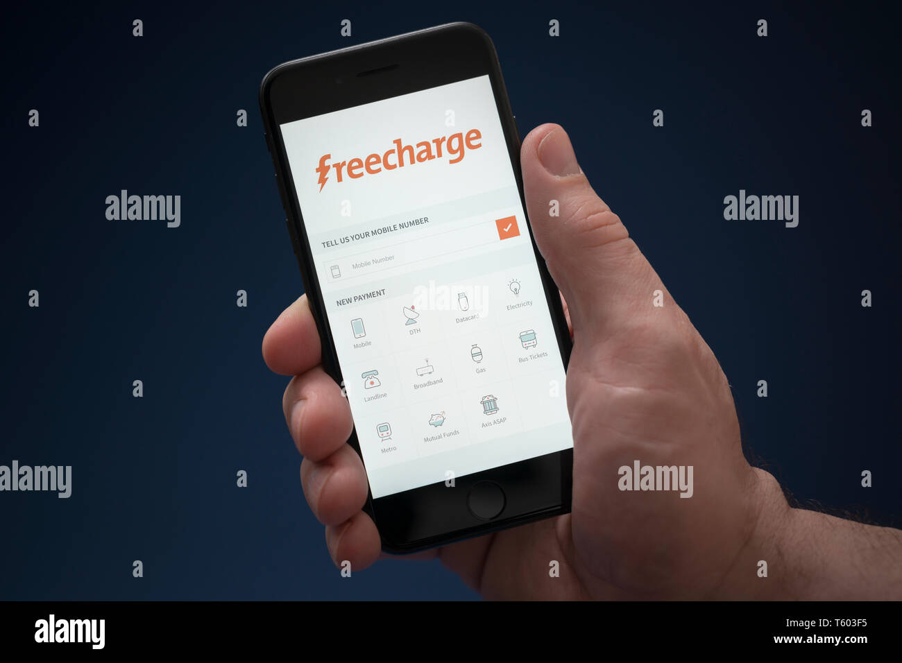 Ein Mann schaut auf seinem iPhone die zeigt den Freecharge Logo (nur redaktionelle Nutzung). Stockfoto