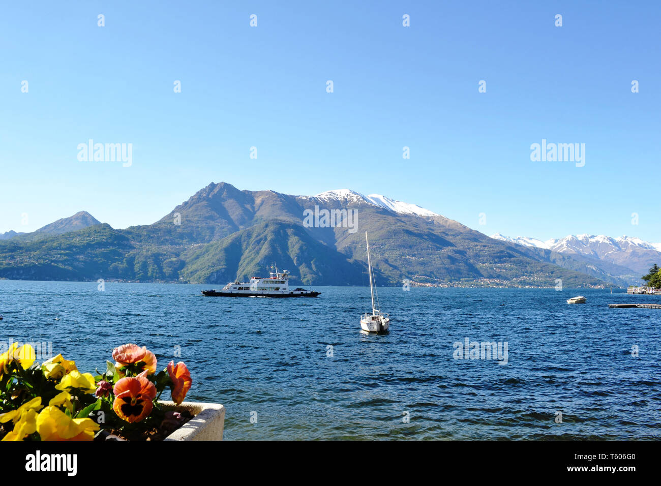 Schönen Panoramablick auf den Comer See von Varenna am Seeufer, ein Passagierschiff verschieben und Berge mit Schnee im Hintergrund, im sonnigen Tag abgedeckt. Stockfoto