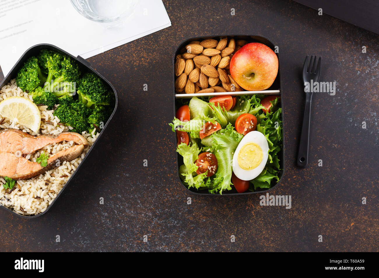 Gesundes Mittagessen im Büro Arbeitsplatz. Takeaway Lunch Boxen mit Ernährung Lebensmittel - Fisch, Gemüse und Obst an Schreibtisch mit Laptop. Stockfoto