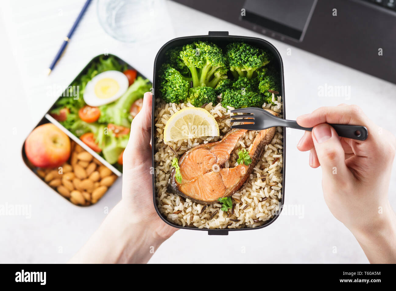 Männliche Hände halten Takeaway Lunch Box mit gesunden Lebensmitteln. Mittagspause im Büro. Stockfoto