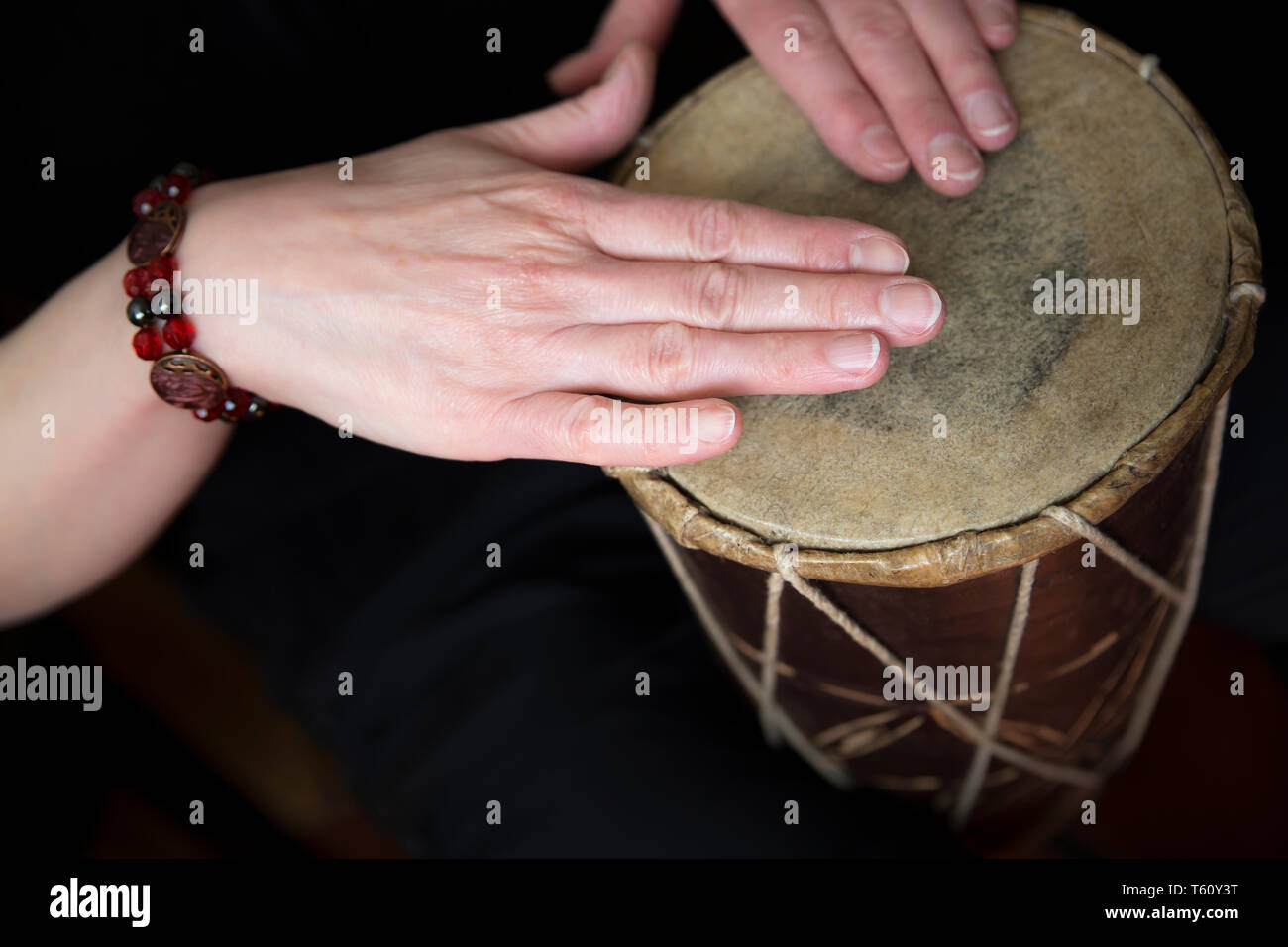 In der Nähe der weiblichen Händen spielen einfache, traditionelle afrikanische Trommel (Gewindebohren Rhythmus mit den Fingerspitzen) beide Hände ruhen auf natürliche Haut Kopf drum. Stockfoto