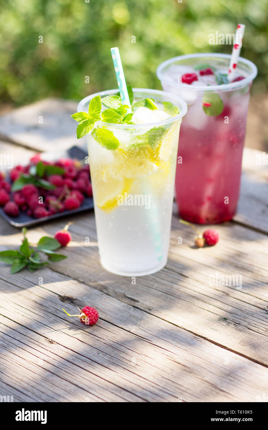 Kalte Getränke. Erfrischende Sommer drink Zitrone, erfrischenden Sommerdrink Himbeere mit Basilikum und Eis auf einem hölzernen Küchentisch. Kopieren Sie Platz. Stockfoto