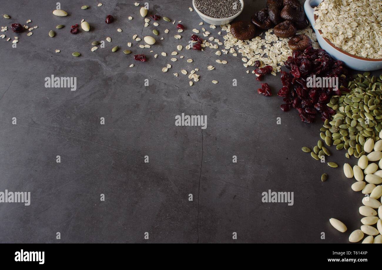 Raw Hafer mit getrockneten Früchten, Samen und Nüsse auf grauem Schiefer Hintergrund mit Kopie Raum Stockfoto