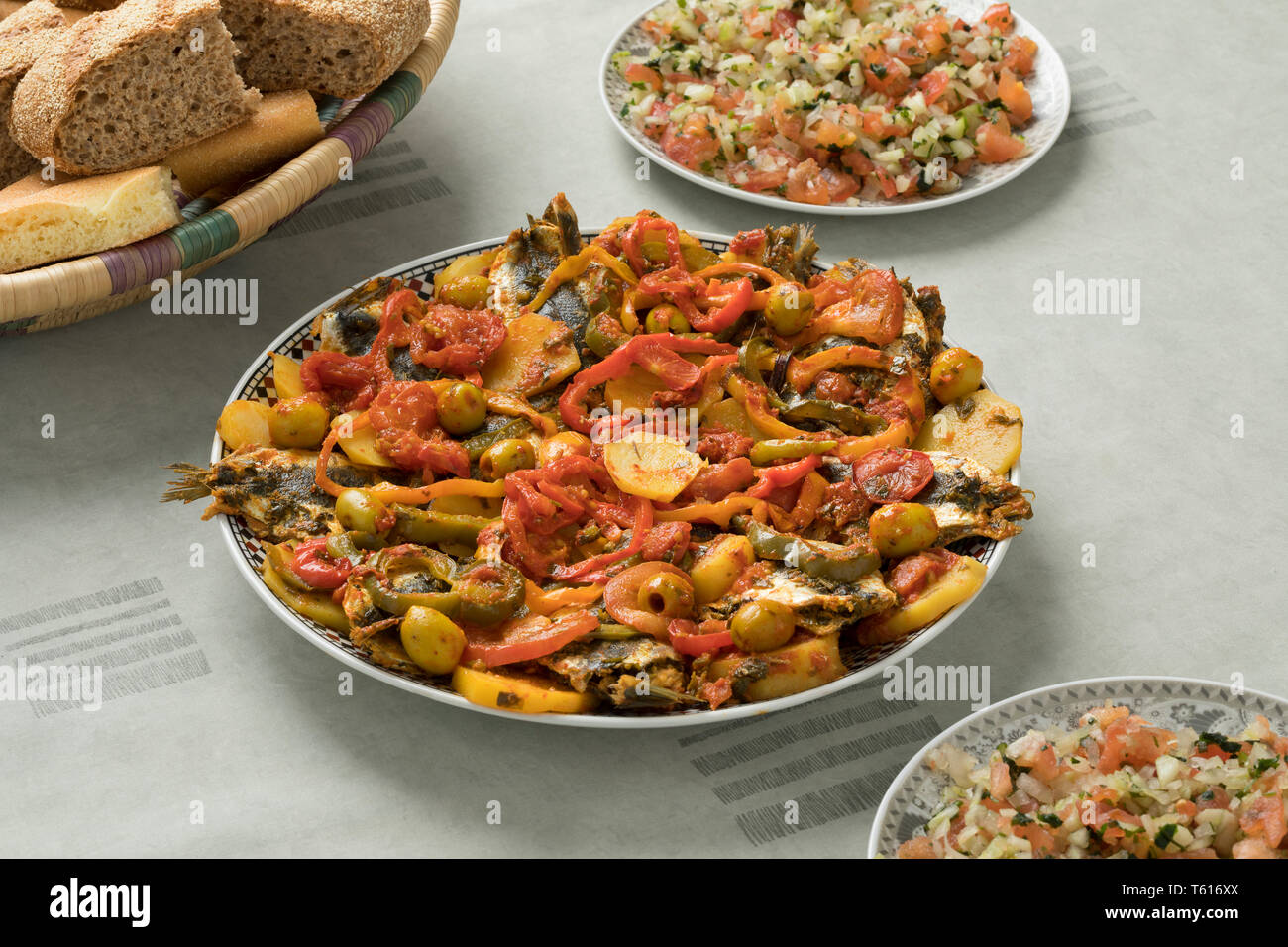Traditionelle marokkanische Gerichte mit Sardinen und Gemüse, Salat und ein Korb mit Brot Stockfoto