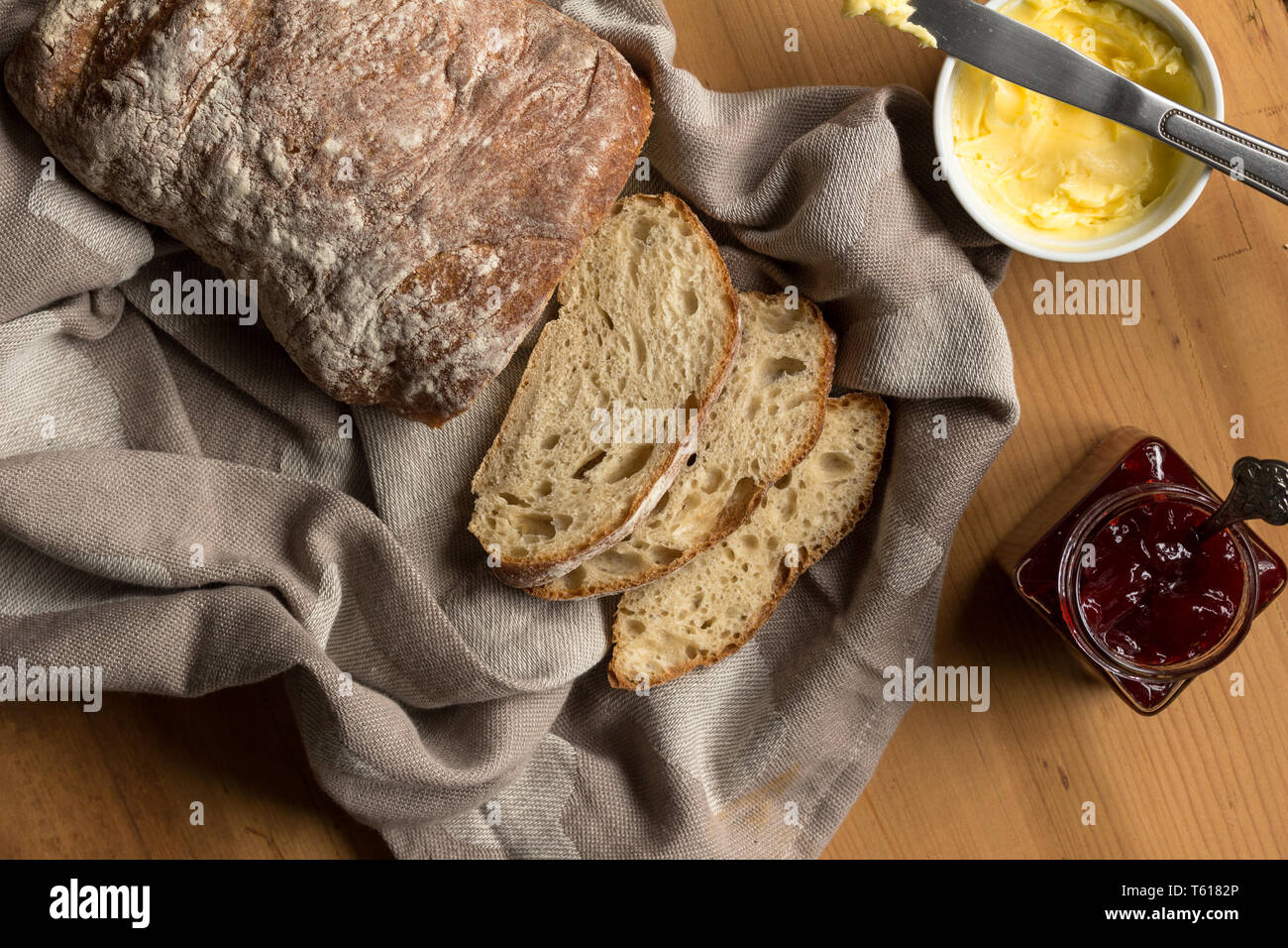 Sauerteigbrot und Scheiben mit Butter und Messer auf Küche Tuch-Overhead Bild Stockfoto