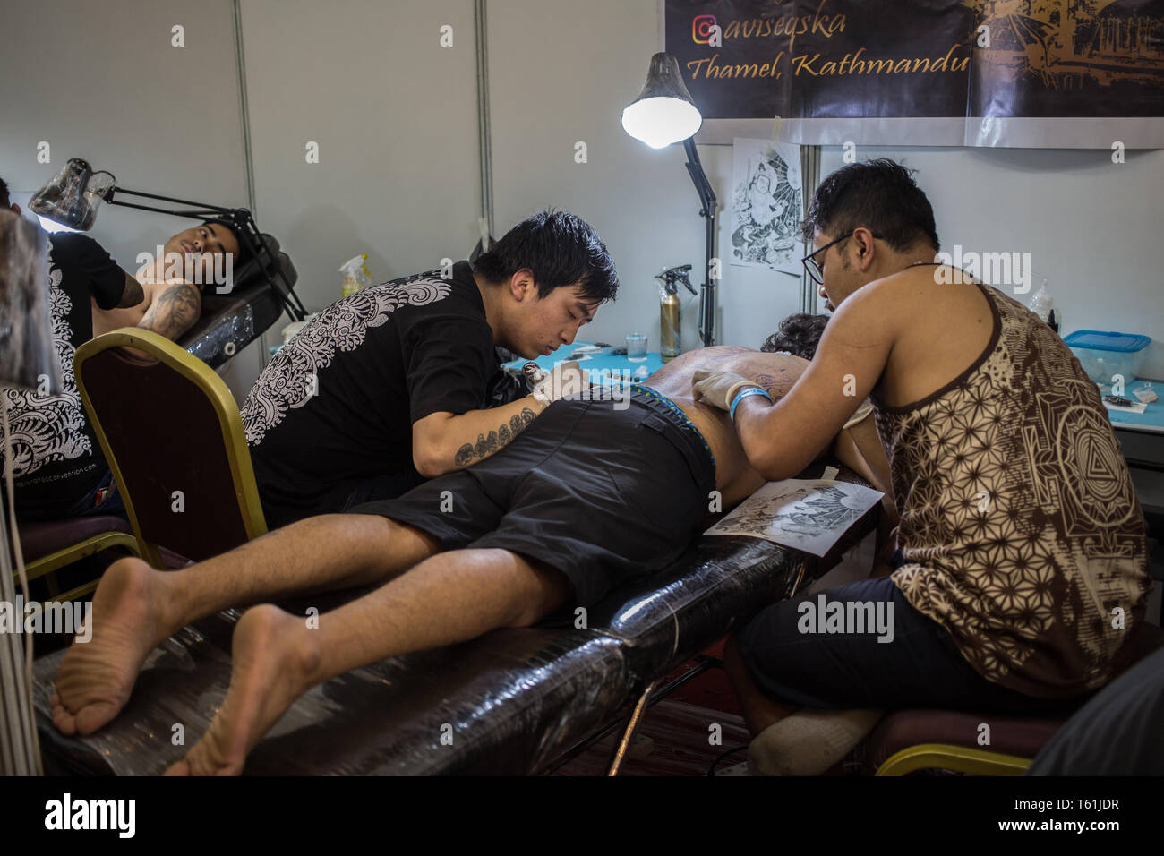 Ein Mann, ein Tattoo von zwei Künstler an einem Stand auf dem jährlichen Tattoo Convention in der Hauptstadt Stockfoto