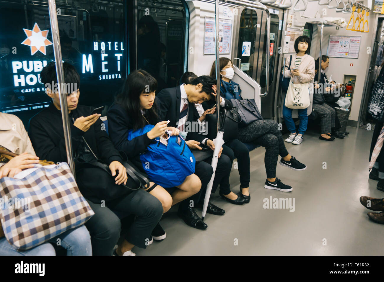 Japanische Leute schlafen und suchen das Mobiltelefon in der Tokioter U-Bahn Wagen Stockfoto