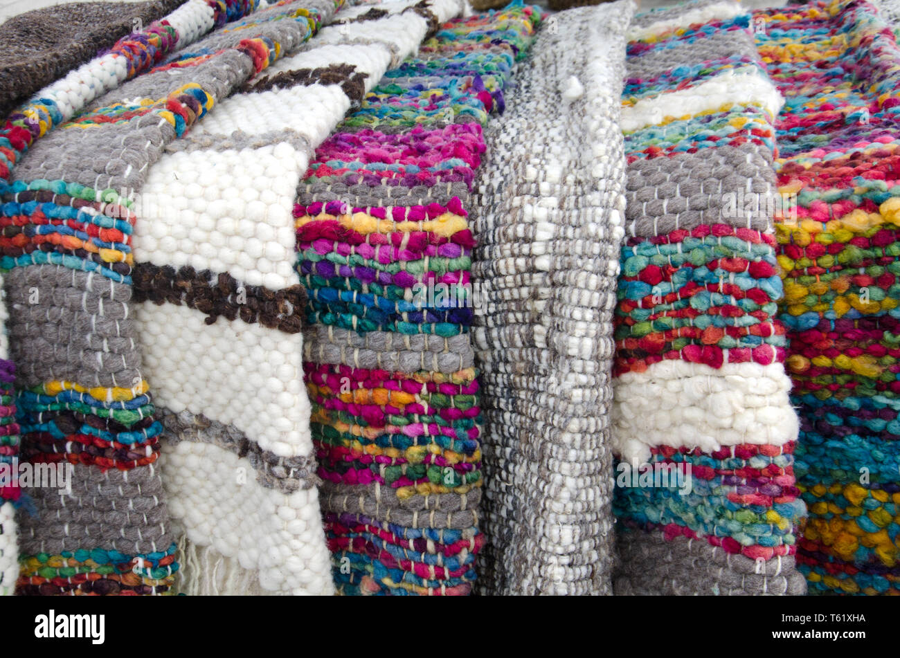 Farbenfrohe Teppiche sind unter der Vielzahl von dicken Stricken Kleidung und Waren auf den Verkauf in den Delcahue Handwerker Markt auf der Insel Chiloé Chile Stockfoto