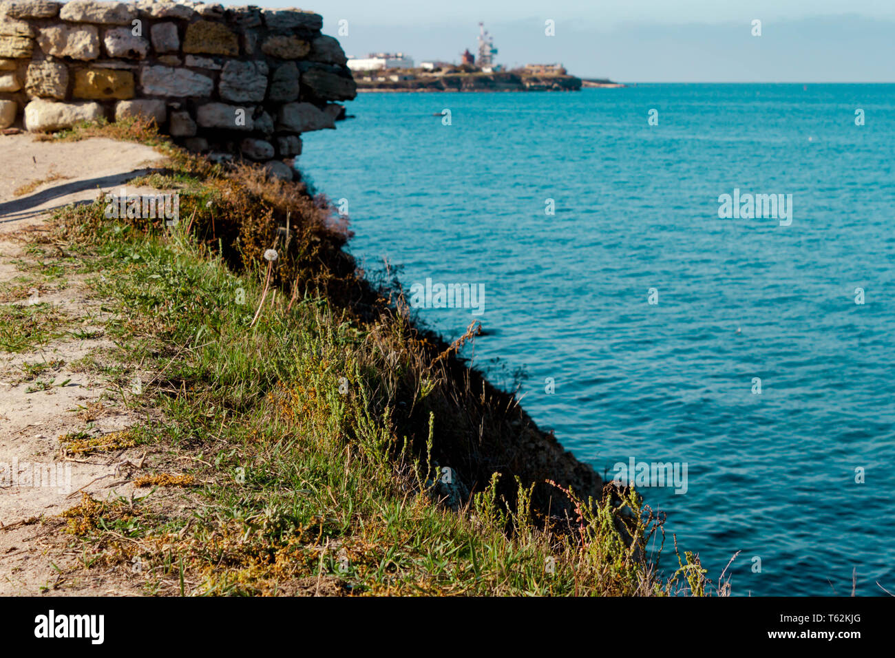 Blaue Meer Blick auf azurblauem Wasser und Steine und Gras an der Küste. Horizont mit Schiffen Hintergrund. Text Platz kopieren. Stockfoto